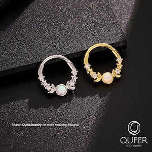 May include: Two hoop earrings, one silver and one gold, each featuring a central opal-like stone and decorative accents of stars and moons. The earrings are designed for body jewelry. The image includes the text "Search OuferJewelry for more stunning designs!"