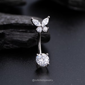 May include: A silver belly button ring with a clear butterfly charm and a large clear round stone.