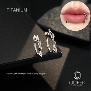 May include: Two silver titanium hoop earrings with cone-shaped spikes. The earrings are displayed on a dark surface. The word "TITANIUM" is at the top left. The image also includes a close-up of a person's lips with similar piercings. The text "Search OuferJewelry for more stunning designs!" is at the bottom.