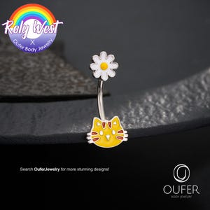 Puede incluir: Un piercing para el ombligo con una cara de gato amarilla y una margarita blanca. El gato tiene detalles rojos y la margarita tiene un centro amarillo. El texto "Roly West Oufer Body Jewelry" está en un círculo de arcoíris. El texto "Search OuferJewelry for more stunning designs!" también es visible.