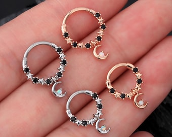 Könnte beinhalten: Drei Ohrringe aus Silber, Gold und Roségold mit einem Halbmond-Anhänger und schwarzen Stern-Akzenten.