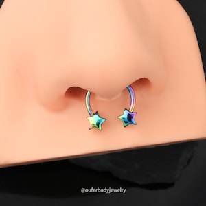 May include: A pair of rainbow-colored nose rings with star-shaped ends. The rings are made of surgical steel and are designed for septum piercings.