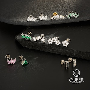 Puede incluir: Una colecci&oacute;n de joyas para el cuerpo, que incluye pendientes para orejas y cart&iacute;lagos. Los pendientes presentan varios dise&ntilde;os, como cristales transparentes con corte marquesa y redondos, gemas verdes y rosas, y un pendiente dorado con cristales transparentes.