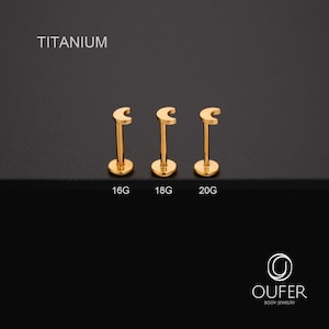 May include: Three gold-coloured titanium lip piercing studs in a crescent moon shape. The studs are labelled 16G, 18G, and 20G. The word "TITANIUM" is printed above the studs. The OUFER Body Jewelry logo is in the bottom right corner.