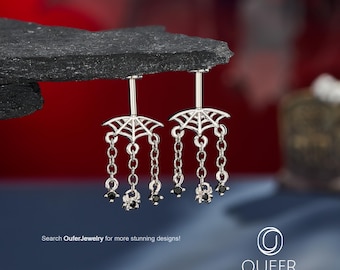 Könnte beinhalten: Ein Paar silberfarbene Bauchnabelpiercings mit einem Spinnennetz-Design am oberen Ende. Jedes Stück hat drei hängende Ketten, an deren Enden zwei kleine schwarze Steine und ein kleiner Spinnenanhänger befestigt sind. Text: Search OuferJewelry for more stunning designs.