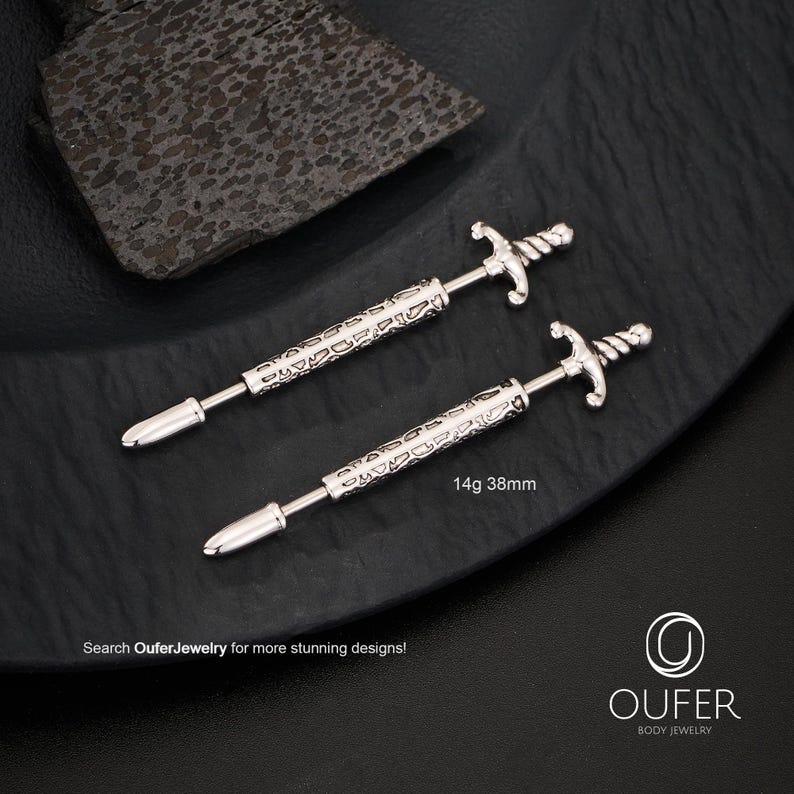 K&ouml;nnte beinhalten: Zwei silberfarbene, schwertf&ouml;rmige K&ouml;rperschmuckst&uuml;cke. Der Schmuck hat einen dekorativen Griff und eine Spitze. Der Text "14g 38mm" ist sichtbar. Das Bild enth&auml;lt auch den Text "Search OuferJewelry for more stunning designs!"