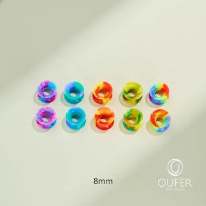 May include: Ten colorful 8mm (0.31 inch) ear gauges in a variety of rainbow hues. The gauges are donut-shaped, with a flared design. The image includes the text "8mm" and the brand name "OUFER BODY JEWELRY".