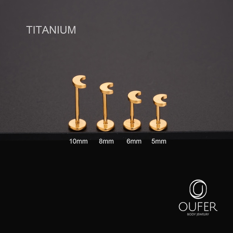 May include: Four gold-coloured titanium lip piercing studs in varying sizes. The studs are shaped like a crescent moon on a post, with sizes 10mm, 8mm, 6mm, and 5mm. The word "TITANIUM" is at the top of the image.