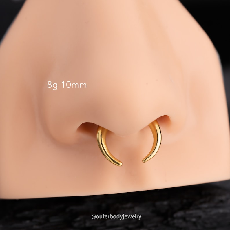 May include: Gold nose ring hoop with a 10mm diameter and 8g gauge. The hoop is shown on a model's nose.