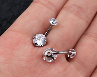 May include: Two silver belly button rings with clear crystal stones. The rings are curved and have a small stone on the top and a larger stone on the bottom.