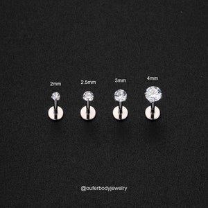 Puede incluir: Cuatro pendientes de bot&oacute;n de plata con piedras de circonita c&uacute;bica transparentes. Las piedras tienen un di&aacute;metro de 2 mm, 2,5 mm, 3 mm y 4 mm. Los pendientes se muestran sobre un fondo negro. @ouferbodyjewelry