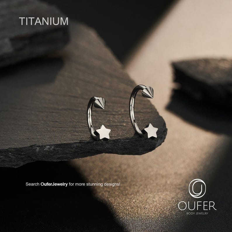 May include: A pair of silver-colored titanium body jewelry, featuring a star and a cone-shaped design. The word "TITANIUM" is at the top. The text "Search OuferJewelry for more stunning designs!" is at the bottom.