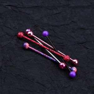 May include: Five different barbell style body jewelry pieces with colorful balls on the ends. The jewelry is made of metal and has a variety of colors, including pink, purple, and black.