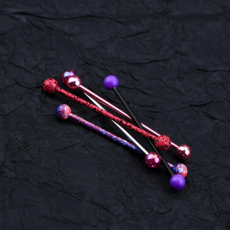 May include: Five different barbell style body jewelry pieces with colorful balls on the ends. The jewelry is made of metal and has a variety of colors, including pink, purple, and black.