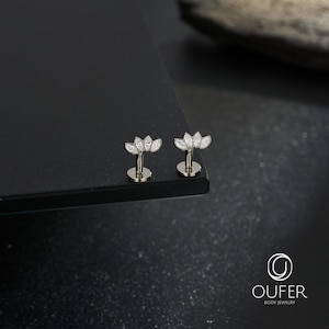 May include: Two silver-toned flat back labret studs featuring a fan-shaped top adorned with five marquise-cut clear crystals arranged in a curved arc. The jewellery pieces are displayed upright, showcasing the metallic posts and the decorative crystal settings.