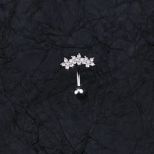 May include: A silver belly button ring with a clear crystal flower design.