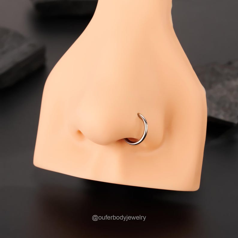 Puede incluir: Un aro de nariz de plata en una cabeza de maniqu&iacute;. El aro es un dise&ntilde;o simple y circular.