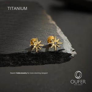 May include: Two gold-coloured stud earrings shaped like eight-pointed stars. The text TITANIUM is visible in the upper left corner, and the text Search OuferJewelry for more stunning designs! and the Oufer Body Jewelry logo are at the bottom.