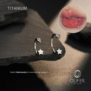 May include: Two silver-colored, curved barbell earrings with a star and cone design. The word "TITANIUM" is printed at the top left. The image also includes a close-up of a lip piercing with a star-shaped stud. The text "Search OuferJewelry for more stunning designs!" is at the bottom.