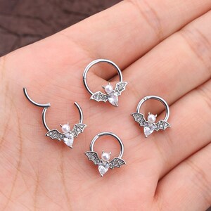 Puede incluir: Cuatro anillos de septum plateados con un dise&ntilde;o de murci&eacute;lago y pedrer&iacute;a transparente. Cada murci&eacute;lago tiene una peque&ntilde;a perla en el centro.