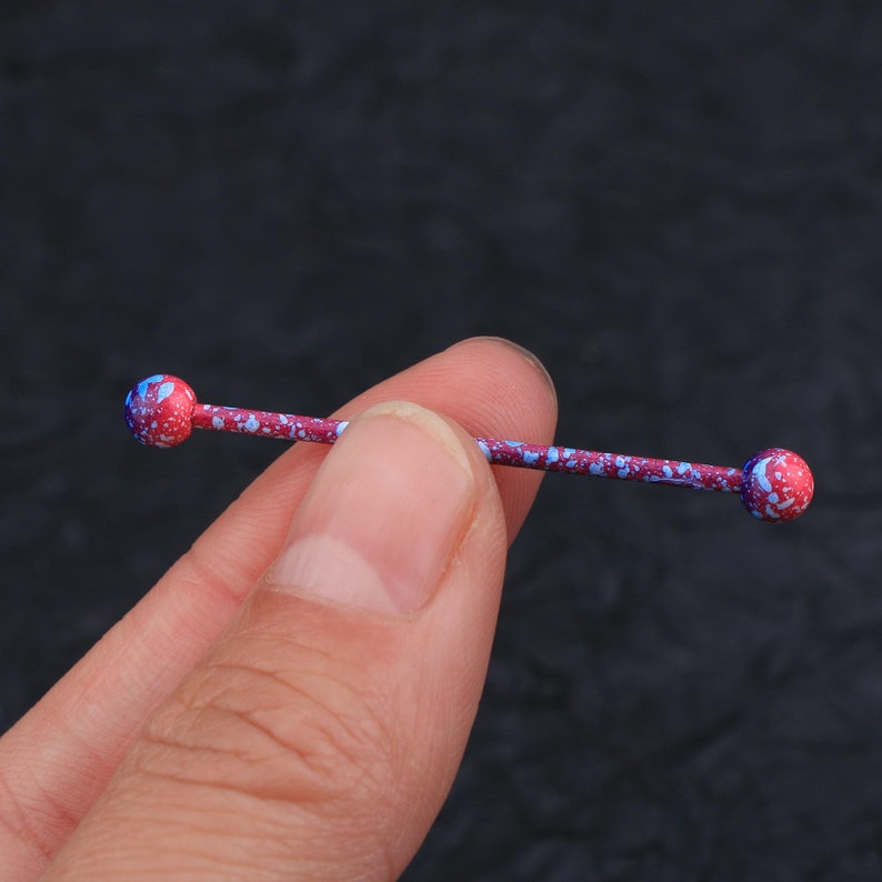 May include: A red and blue barbell with a speckled pattern. The barbell is made of metal and has two round ends.