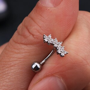 May include: Silver belly button ring with a clear crystal flower design.