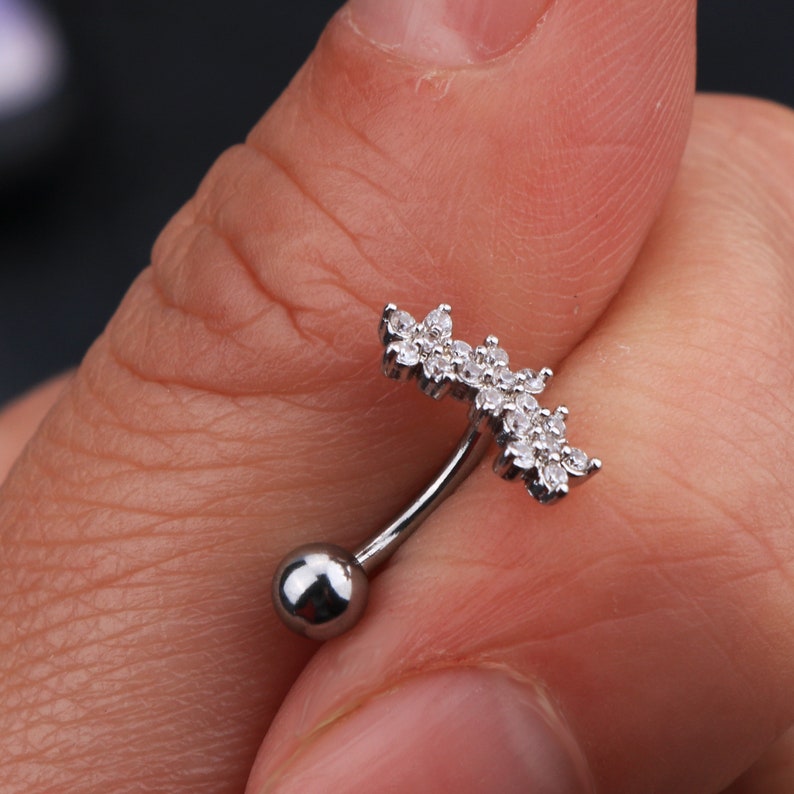 May include: Silver belly button ring with a clear crystal flower design.