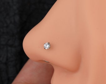 May include: A clear nose ring with a small, round, clear gemstone.
