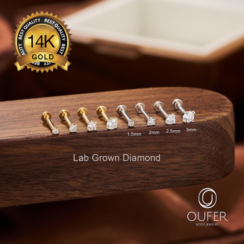 Puede incluir: Una colecci&oacute;n de pendientes de diamantes cultivados en laboratorio de varios tama&ntilde;os, exhibidos sobre una superficie de madera. Los pendientes est&aacute;n engastados en postes de oro y plata, con tama&ntilde;os de diamante que van de 1,5 mm a 3 mm.