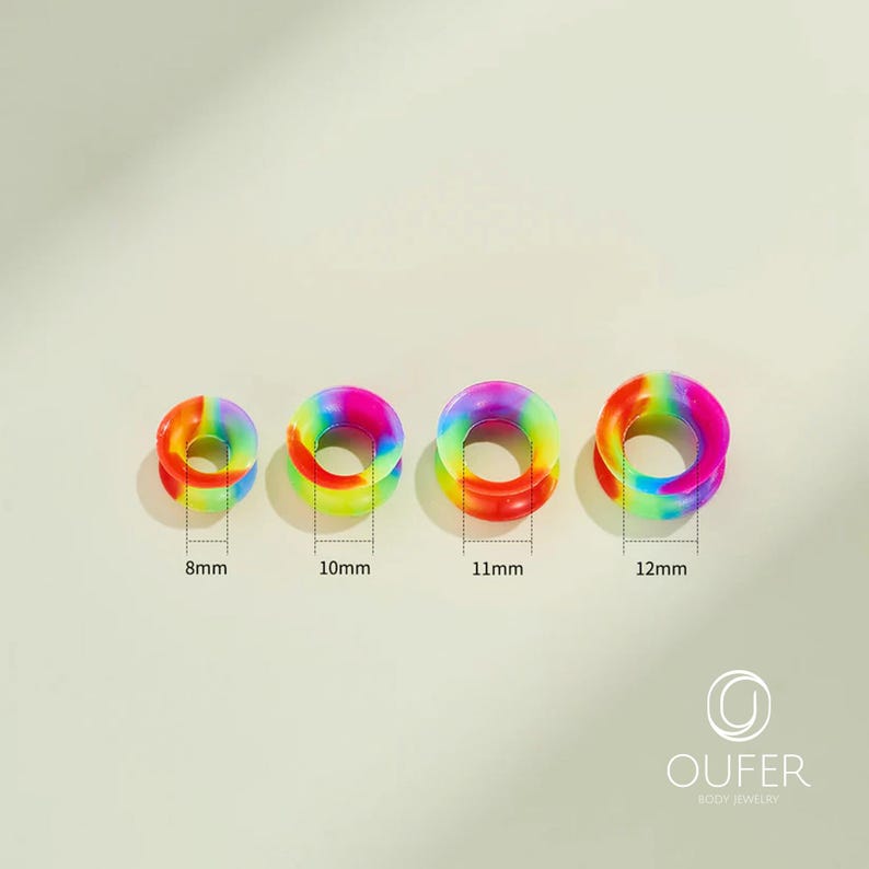 May include: Four rainbow-colored ear gauges in varying sizes: 8mm, 10mm, 11mm, and 12mm. Each gauge features a vibrant blend of colors, including red, orange, yellow, green, blue, and purple. The gauges are made of a smooth material.