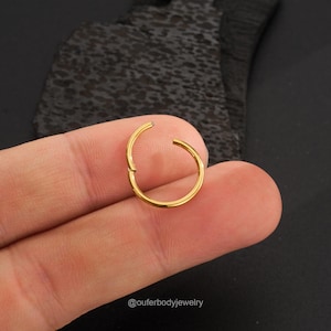 May include: Gold seamless clicker ring for body piercing. The ring is open and ready to be inserted.