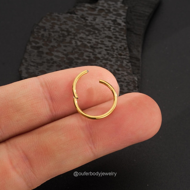 May include: Gold seamless clicker ring for body piercing. The ring is open and ready to be inserted.