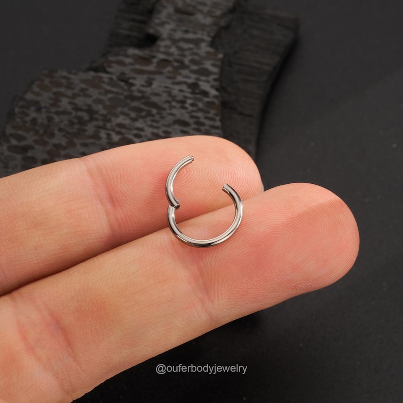 Puede incluir: Un anillo de piercing corporal sin costuras de plata. El anillo est&aacute; abierto y listo para ser insertado en un piercing.