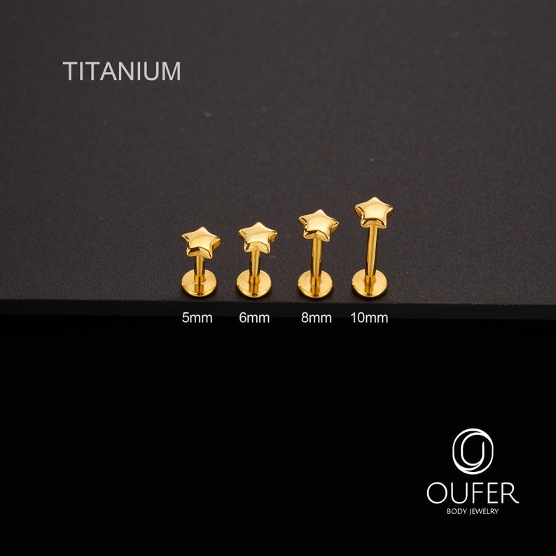K&ouml;nnte beinhalten: Goldfarbene Lippenpiercing-Stecker in Sternform in den Gr&ouml;&szlig;en 5 mm, 6 mm, 8 mm und 10 mm. Das Wort "TITANIUM" ist &uuml;ber den Steckern aufgedruckt. Die Stecker werden auf schwarzem Hintergrund dargestellt. Der Markenname "OUFER BODY JEWELRY" ist unten aufgedruckt.