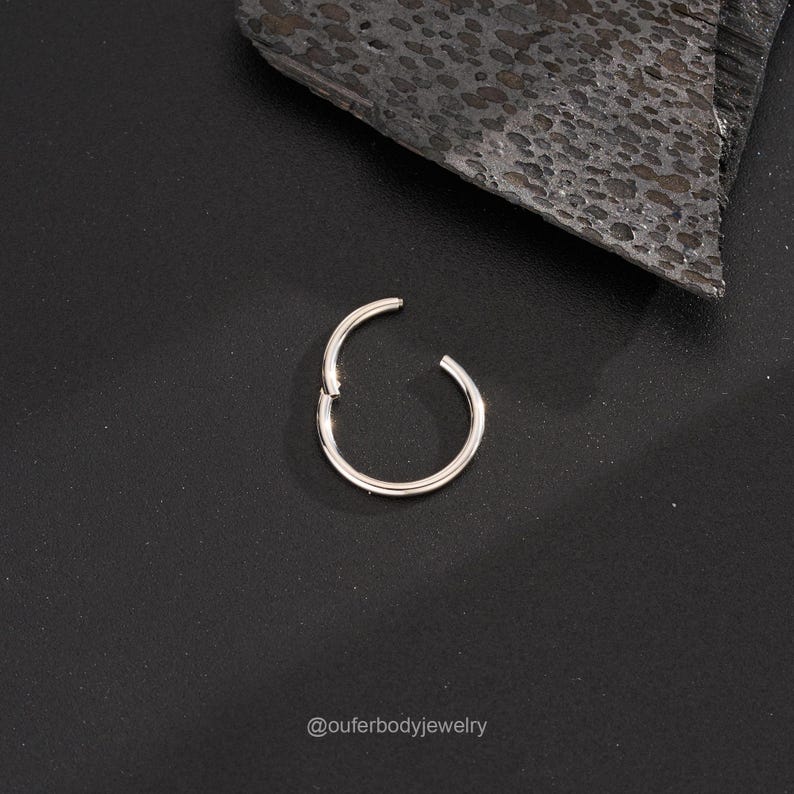 Puede incluir: Un anillo de piercing corporal sin costuras de plata. El anillo est&aacute; abierto y listo para ser insertado.