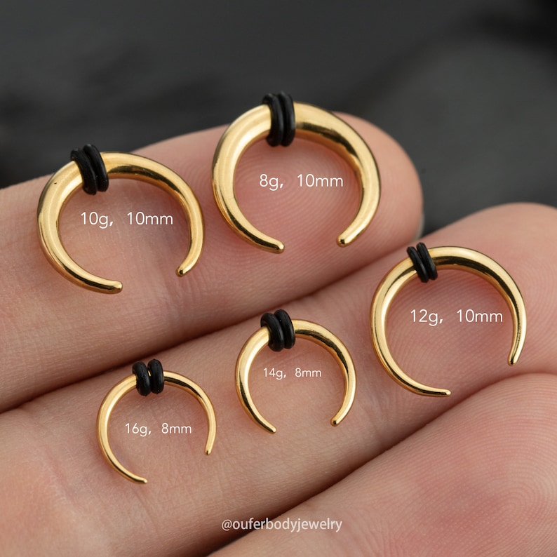 May include: Five gold horseshoe-shaped nose rings with black o-rings. The rings are sized 8g, 10mm; 10g, 10mm; 12g, 10mm; 14g, 8mm; and 16g, 8mm.