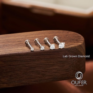 Puede incluir: Cuatro pendientes labret de plata con diamantes redondos cultivados en laboratorio, transparentes, de diferentes tama&ntilde;os. Las joyas se exhiben sobre una superficie de madera oscura. El texto "Lab Grown Diamond" es visible.
