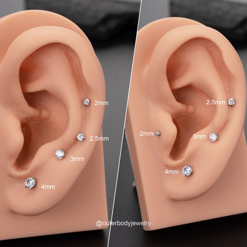 Puede incluir: Primer plano de una oreja con cinco pendientes de gema transparente de diferentes tama&ntilde;os. Los pendientes miden 2 mm, 2,5 mm, 3 mm, 4 mm y 2,5 mm. La leyenda dice "@outerbodyjewelry".