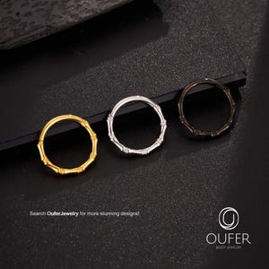 May include: Three hoop earrings in gold, silver, and black, each with a bamboo-like design. The earrings are displayed on a dark surface. Text on the image reads "Search OuferJewelry for more stunning designs!" and "OUFER BODY JEWELRY".