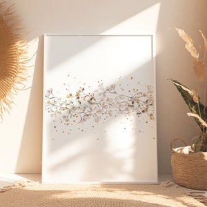 May include: A white framed print with a watercolor illustration of a branch of white flowers with gold glitter accents. The print is hanging on a white wall with a woven sunburst mirror and a wicker basket with dried plants.