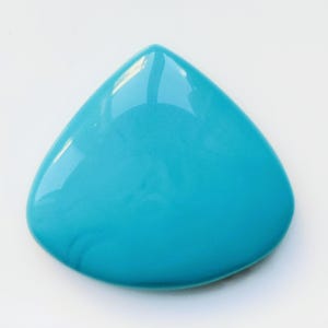 May include: A teardrop-shaped, turquoise-colored object with a glossy finish. The smooth surface reflects light, creating highlights. The object is set against a plain white background, emphasizing its shape and color.