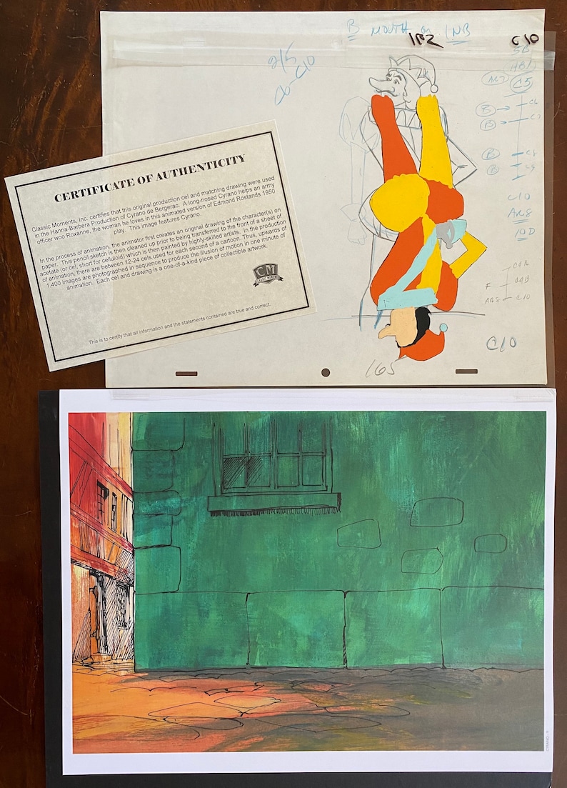 May include: An original animation cel from the Hanna-Barbera production of Cyrano de Bergerac, featuring a colorful jester character. The image includes a certificate of authenticity and a background scene of a building with a green wall.