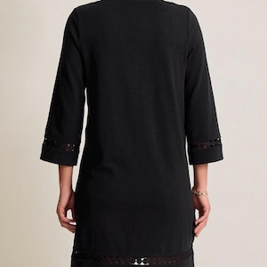 May include: Black dress with three-quarter sleeves and a decorative lace trim at the hem and sleeve cuffs. The dress has a simple, classic design, suitable for various occasions.