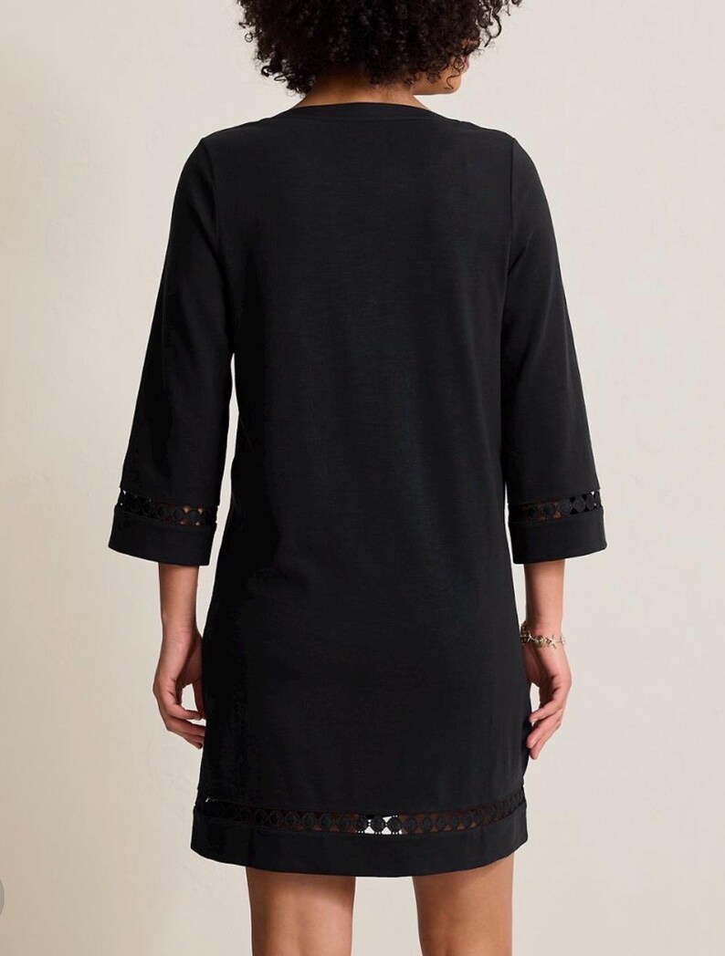 May include: Black dress with three-quarter sleeves and a decorative lace trim at the hem and sleeve cuffs. The dress has a simple, classic design, suitable for various occasions.