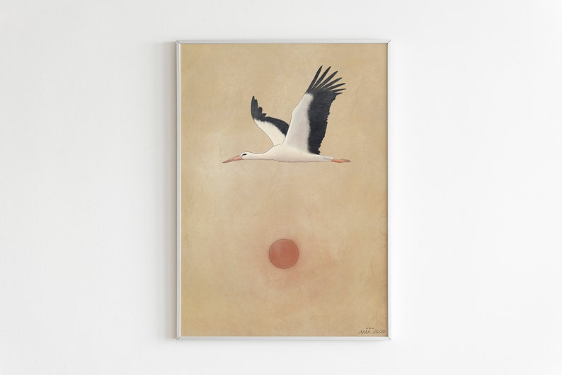 May include: A framed art print featuring a stork in flight against a beige background. The stork is depicted with black and white wings, a red beak, and pink legs. A red circle, possibly representing the sun, is below the bird.