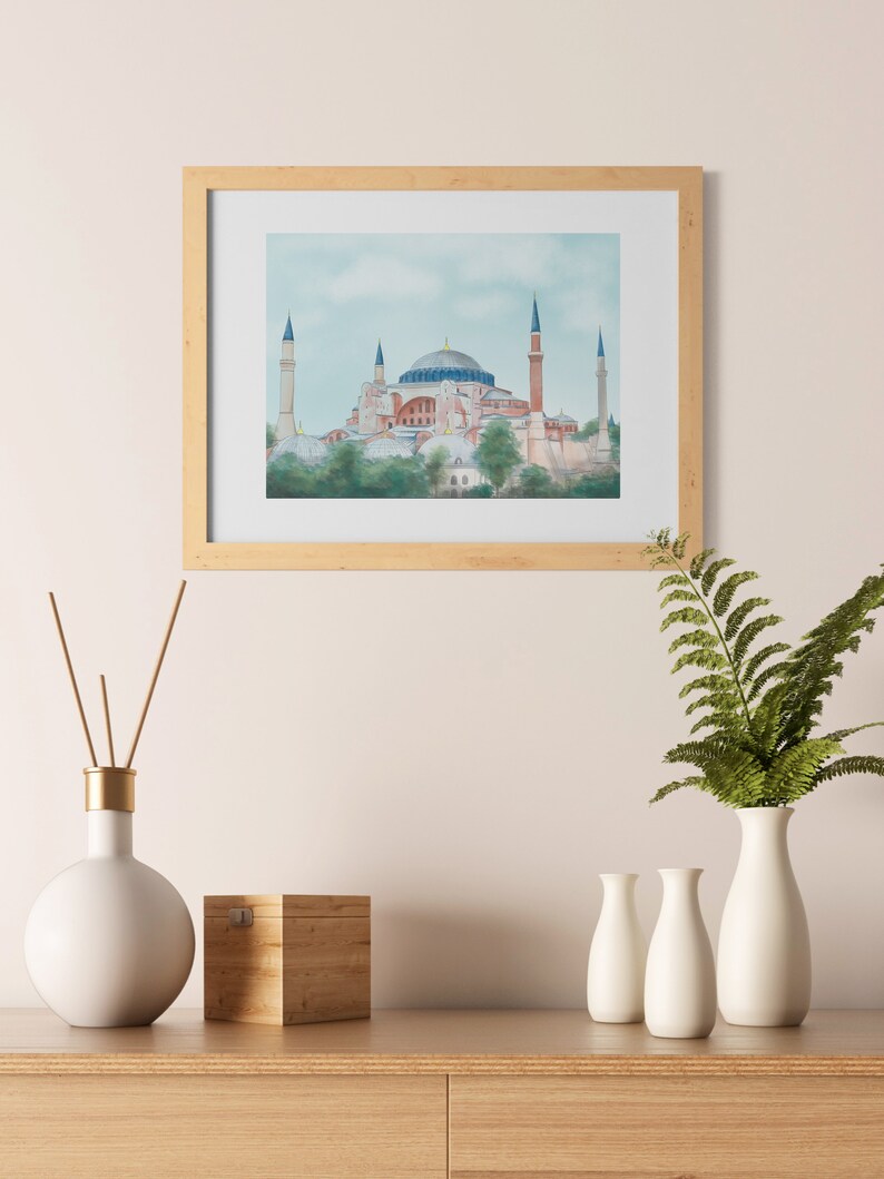 Puede incluir: Una pintura de acuarela enmarcada de la mezquita de Santa Sof&iacute;a en Estambul, Turqu&iacute;a. La mezquita est&aacute; representada en un esquema de color azul claro, rosa y blanco con un cielo azul claro en el fondo.