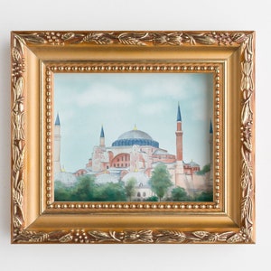 Puede incluir: Una pintura enmarcada de la mezquita de Santa Sof&iacute;a en Estambul, Turqu&iacute;a. La pintura est&aacute; en un marco dorado con detalles ornamentados. La mezquita se representa en un cielo azul claro con nubes blancas. La mezquita es de color marr&oacute;n claro con una gran c&uacute;pula y minaretes.