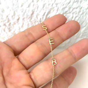Puede incluir: Un collar de cadena de oro con las letras "SEB" colgando.