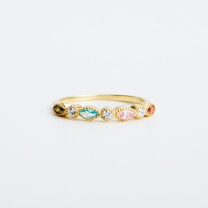 Peut inclure: Une bague en or avec une rang&eacute;e de pierres pr&eacute;cieuses de forme marquise color&eacute;es. Les pierres sont serties dans une bande d'or et dispos&eacute;es en arc-en-ciel.