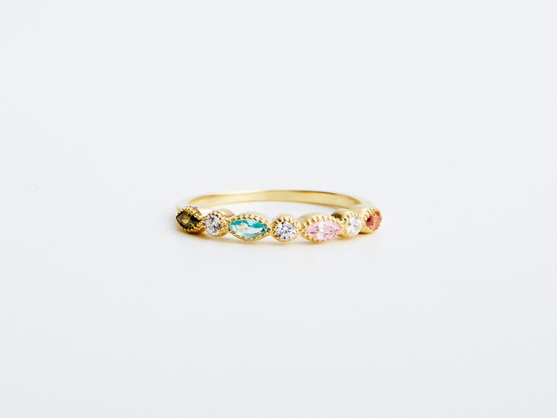 Peut inclure: Une bague en or avec une rang&eacute;e de pierres pr&eacute;cieuses de forme marquise color&eacute;es. Les pierres sont serties dans une bande d'or et dispos&eacute;es en arc-en-ciel.